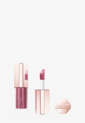 Gloss à lèvres liquide dans une base transparente avec une teinte rose, doté d'un applicateur angulé et d'un emballage géométrique en or rose. Agrémenté de la marque.