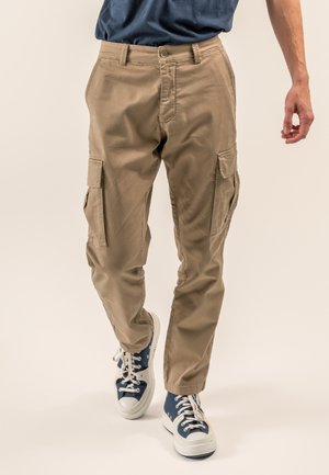 Khakifarbene Cargo-Hosen verfügen über mehrere Seitentaschen, ein gerades Bein-Design und ein strapazierfähiges Baumwollmischgewebe. Sie werden mit blauen Sneakers getragen.