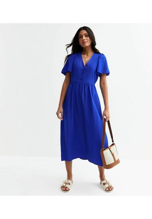 Blue midi dress with short flutter sleeves, button detailing, and a gathered waist. Paired with white sandals and a brown crossbody bag.