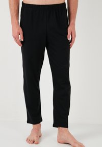 Pantaloni de lounge din bumbac negru, cu un tiv elastic, design cu picior drept și buzunare laterale. Textură moale și material ușor.