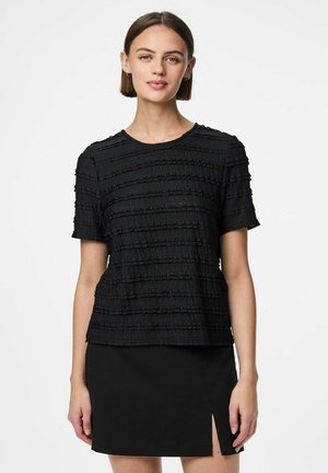 Top noir à manches courtes avec un motif texturé et des volants horizontaux, col rond et coupe décontractée. Porté avec une jupe noire.