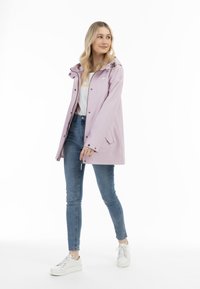 Lila waterdichte jas met capuchon, zilverkleurige hardware en drukknoopsluiting. Draag boven een wit shirt en blauwe jeans met witte sneakers.