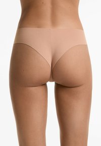 Naadloze nude hipster onderbroek met een gladde textuur, lage taille en minimale bedekking, voorzien van zachte randen en een lichtgewicht gevoel.