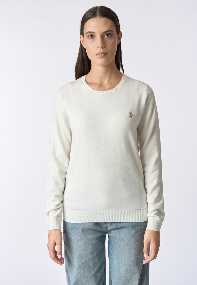 Maglione a maglia color crema con maniche lunghe, scollatura rotonda e orlo a coste. Presenta un piccolo logo ricamato sul lato sinistro del petto.