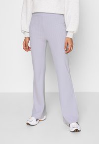 Ljusgrå ribbade flared byxor med hög midja. Slät textur med subtila vertikala ränder. Matchade med vita och svarta sneakers.