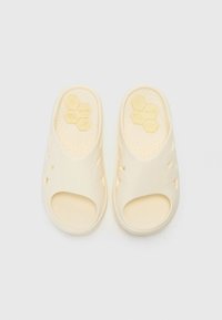 Krémszínű, gumiból készült, slip-on stílusú szandál, nyitott orrú tervezéssel, szellőző lyukakkal és hatszögletű mintázatú, texturált talppal.