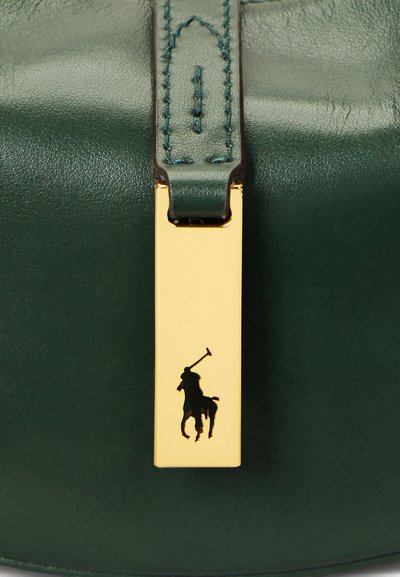 Geantă verde din piele, cu accesorii aurii și un închizător rectangular care afișează silueta unui jucător de polo negru. Finisaj texturat, design elegant.