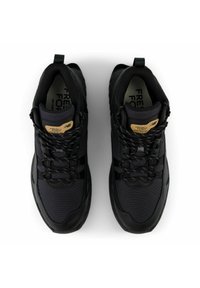 Svarta sportskor gjorda av mesh och syntetmaterial med en texturerad yta, som har snörningsdesign och en dragflik vid hälen.