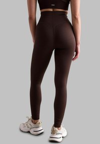 Pruun ribakate legginsid kõrgema taljega ja istuva disainiga, millel on sujuv tekstuur ja tagasi peene logo detail.