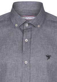 Grå linned skjorte med knaplukning og krave, med hvide knapper og en lille sort kolibri broderet på venstre bryst.