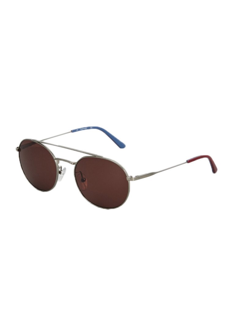 Lunettes de soleil aviateur en métal avec verres marron, monture argentée, accents de temple bleu et rouge, et un design fin et léger.