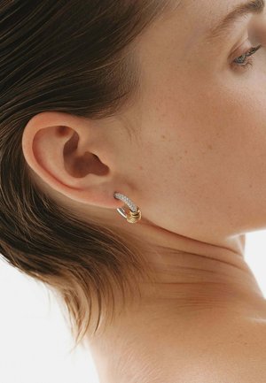 Aro de pendientes de plata y oro con un diseño texturizado; presenta una parte curva de plata y tres anillos dorados apilados.