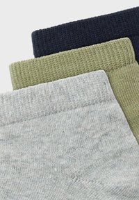 Tres pares de calcetines apilados: azul marino oscuro, verde oliva y gris claro. Cada uno tiene una tela de punto texturizada y un diseño de puño acanalado.