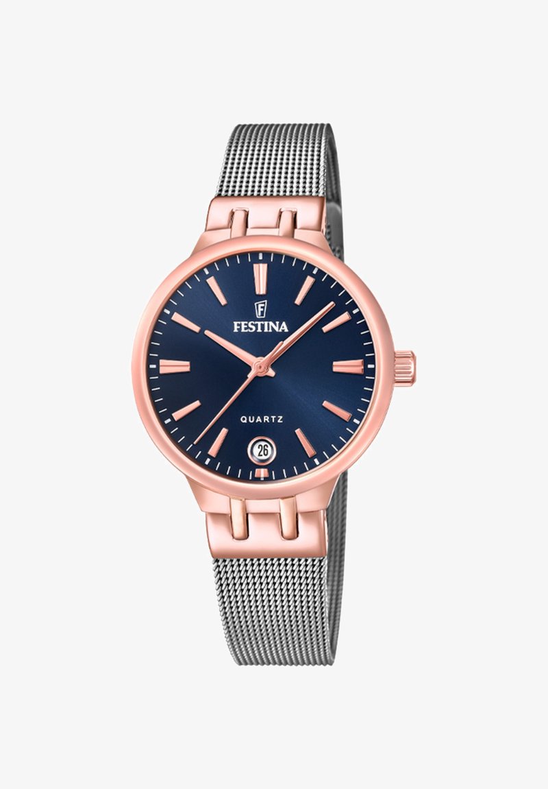 Křemíkový hodinky s námořnickou modrou ciferníkem, růžově zlatými akcenty, zobrazením data a stříbrným síťovým páskem. Vyznačují se tenkými hodinovými indexy a kulatým pouzdrem.