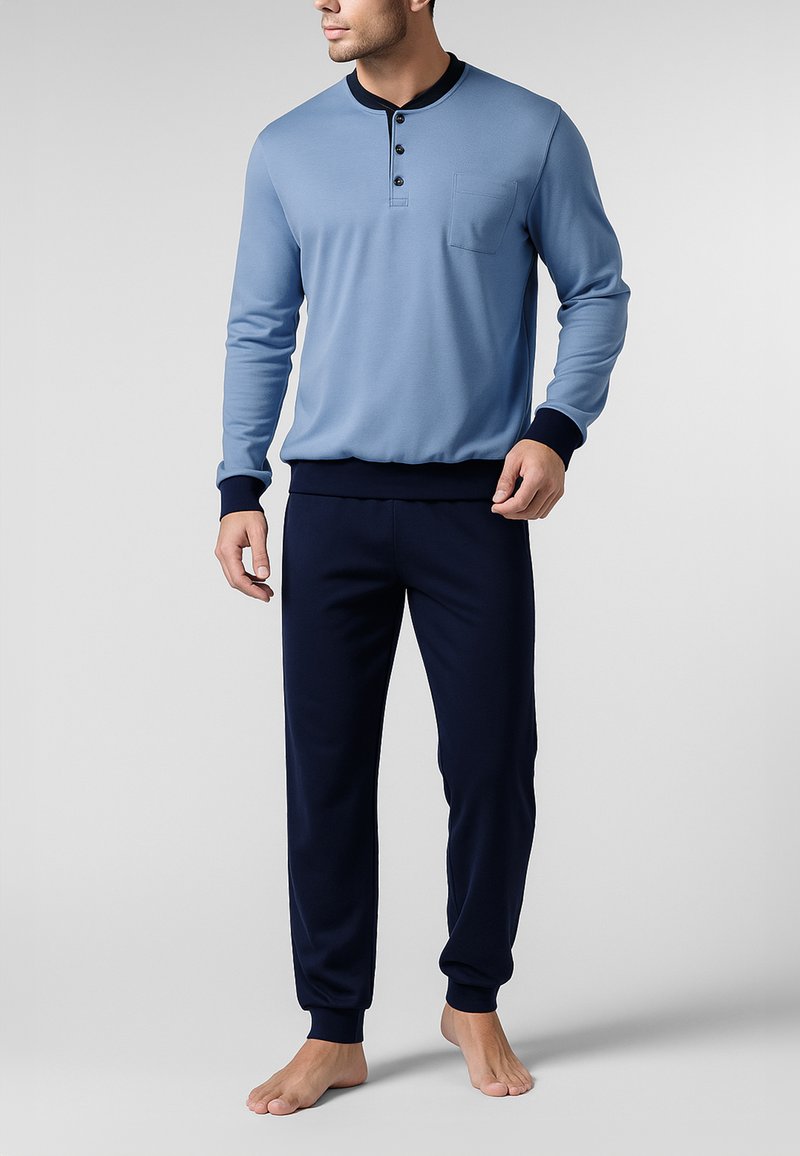 Maglia henley a maniche lunghe blu con tre bottoni e taschino sul petto, abbinata a pantaloni con vita elastica navy. Entrambi realizzati in tessuto morbido.