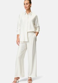 White striped shirt with buttons and long sleeves, paired with matching wide-leg pants; both made from a smooth fabric.