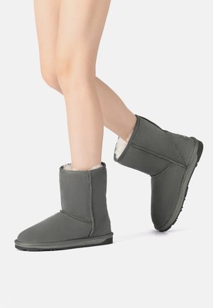 Gray ankle-height boots made from soft suede, featuring a fluffy interior lining and a textured rubber sole. Iconic design with simple stitching.