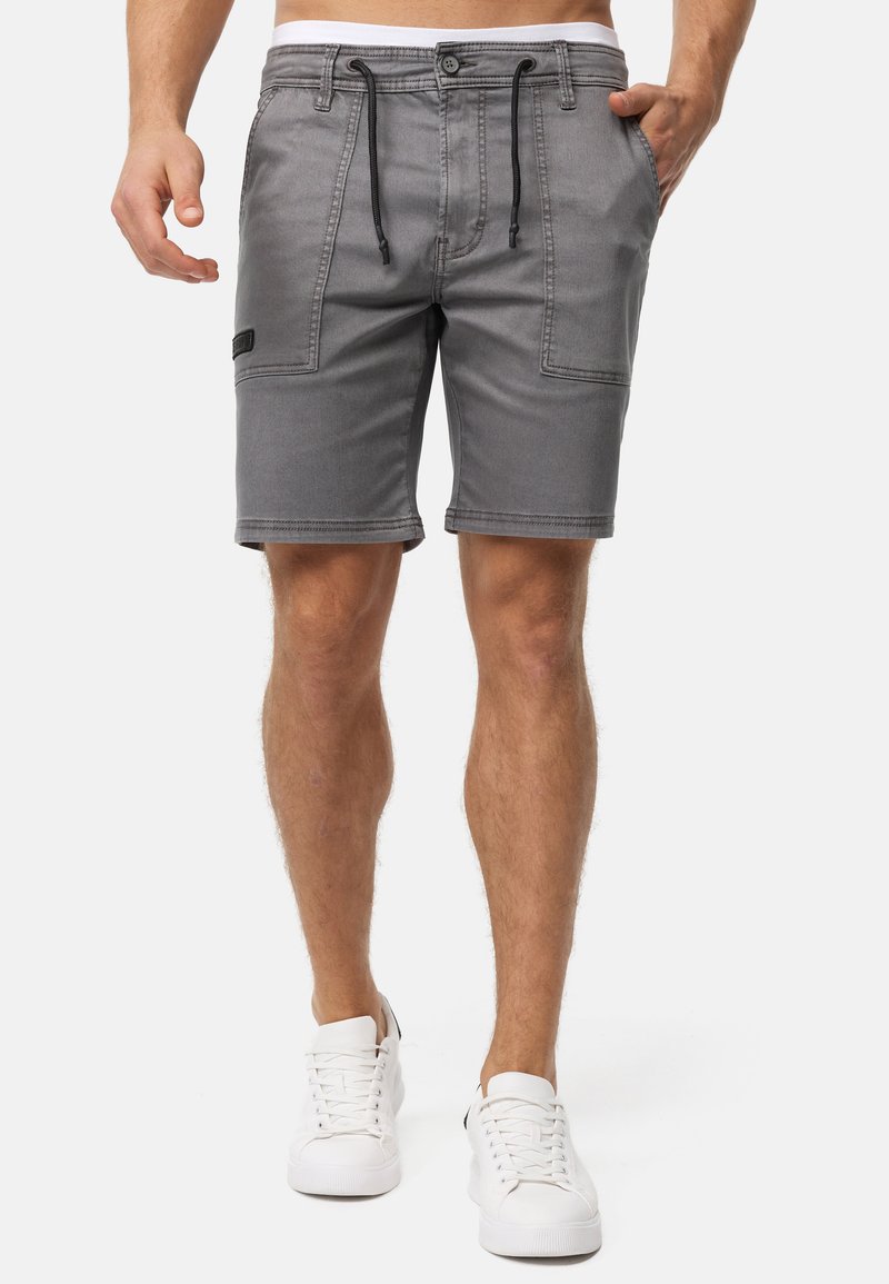 Grå shorts lavet af denim med snoretræk i taljen, sidelommer og et lille logo-patch på venstre side. Glat tekstur og tætsiddende design.