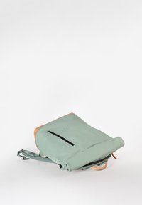 Zaino verde menta con dettagli marroni, design a soffietto, spallacci regolabili e tasca frontale con zip. Texture liscia e forma moderna.