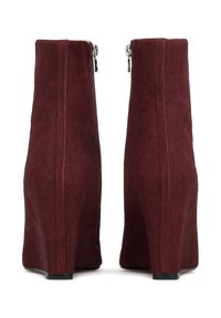 Burgundy faux fur ankle boots with wedge heels, side zippers, and smooth texture. Features a clean, structured design with a slight sheen.