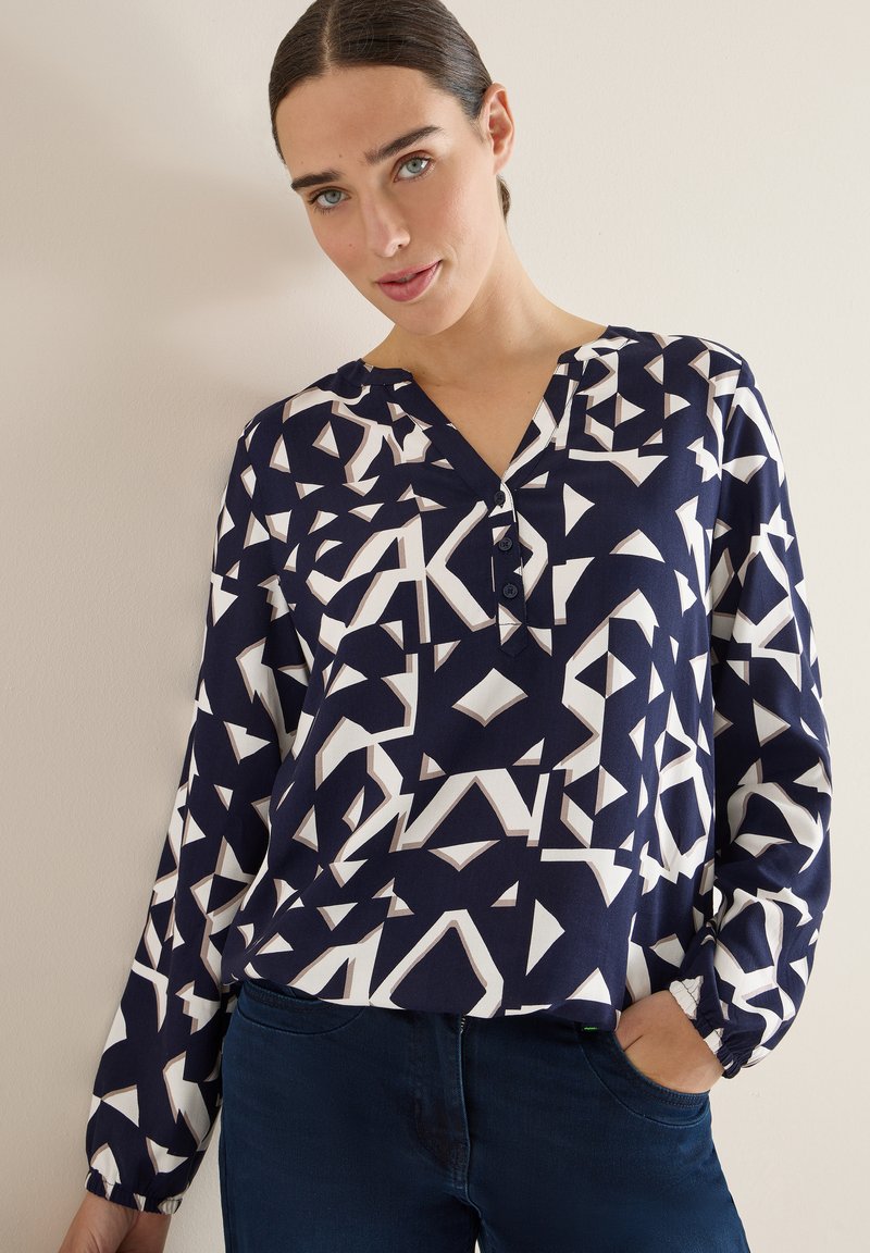 Marineblouse met geometrische witte patronen, V-hals, knoopsluiting en lange mouwen met elastische manchetten. Zachte stof, relaxte pasvorm.