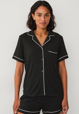 Zwart pyjama set met korte mouwen en witte piping, bestaande uit een overhemd met knopen en shorts, gemaakt van zachte stof met een zakdetail.