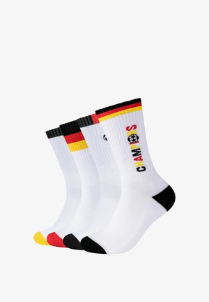 Vier paar witte enkelsokken met zwarte, rode en gele accenten, waarvan één paar de tekst "CHAMPS" toont met een voetbalicoon.