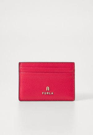 Red leather cardholder with textured surface, featuring four card slots and gold "FURLA" logo, finished with black edging. Compact design.