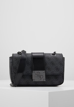 Schwarze Designer-Schultertasche mit Monogramm-Muster, einem dicken glänzenden Trägerabschnitt und einem silbernen Schlossverschluss mit Markeninitialen, auf einer weißen Oberfläche präsentiert.