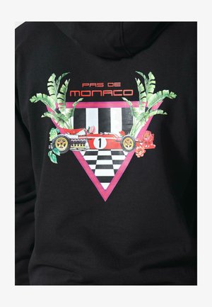 Hanorac negru cu un grafic al unei mașini de curse roșii cu „1” pe ea, încadrată de frunze și flori verzi, peste un fundal în carouri și un triunghi roz.