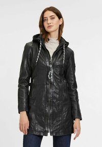 Schwarze Lederjacke mit Kapuze, silbernem Reißverschluss, Kordelzugdetails, seitlichen Taschen und tailliertem Schnitt. Glatte Textur mit minimalem Glanz.