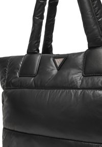 Borsa tote trapuntata nera realizzata in materiale morbido e lucido, con due manici robusti e un dettaglio logo triangolare sulla parte anteriore.