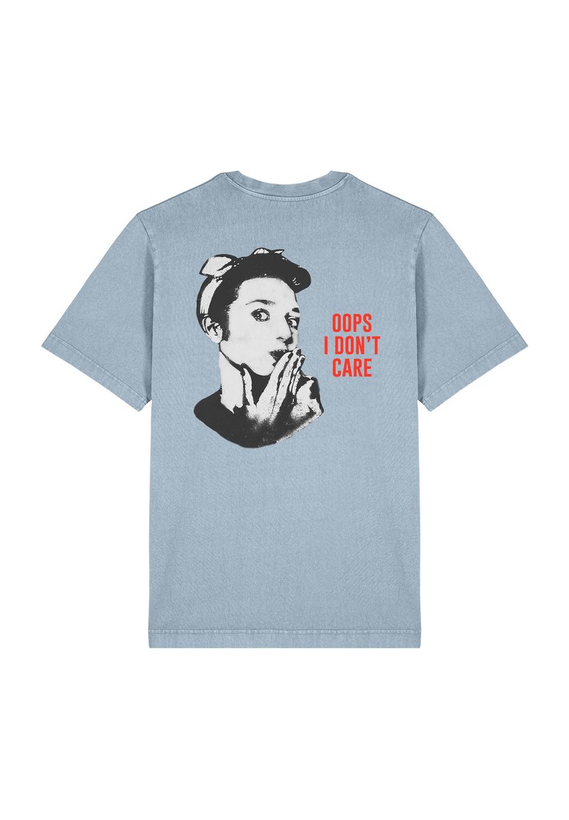 T-shirt bleu clair à manches courtes avec un graphique noir et blanc d'une femme portant un bandeau, texte en rouge : "OUPS JE M'EN FICHE."