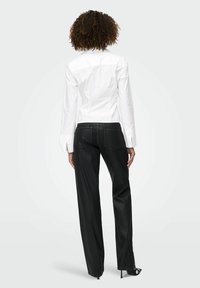 Chemise blanche à manches longues, associ�ée à un jean noir à taille haute et coupe large. Design minimaliste avec une coupe ajustée.