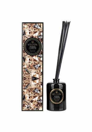 Voluspa Ambre Lumiere diffuser i en sort glasflaske med mørke rørstænger. Emballagen har et geometrisk mønster i guld- og beige nuancer.