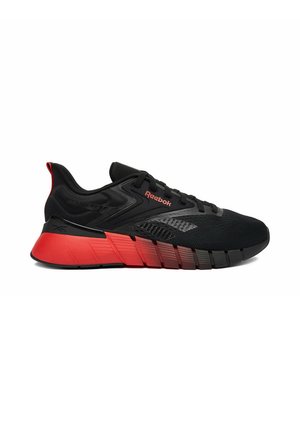 Schwarz-roter Reebok Sportschuh mit Mesh-Obermaterial, dicker segmentierter Sohle und Schnürdesign, seitlich auf weißem Hintergrund dargestellt.