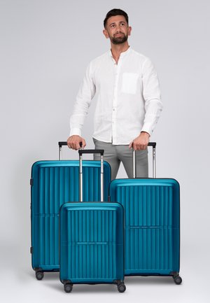 Trois valises de rangement de couleur teal avec un design à stries verticales, coque rigide, poignées rétractables et roulettes à 360 degrés.