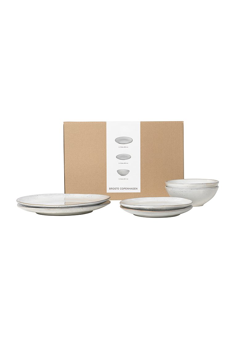Drei keramische Schalen in einer hellen Farbe mit gepunkteter Textur und einem glatten, geschwungenen Design, verpackt in einem braunen Karton.