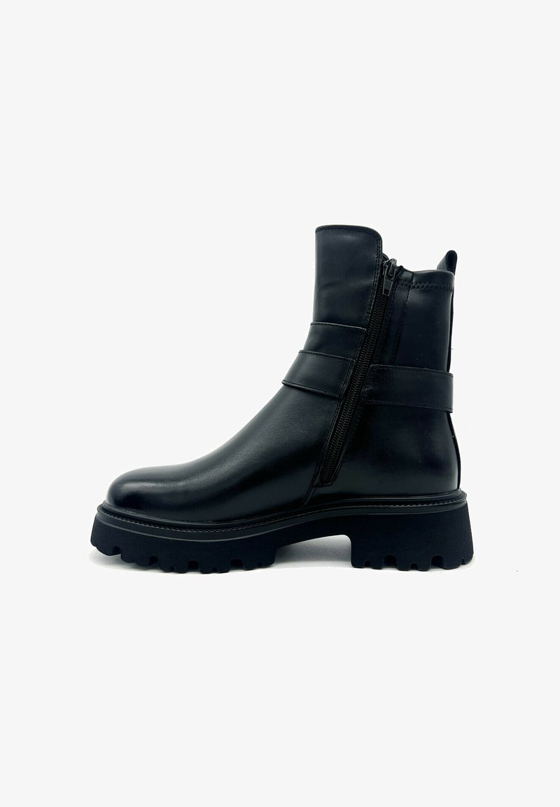 Stivale alla caviglia in pelle nera con chiusura a zip, texture liscia, con cinturini in evidenza e suola in gomma spessa e scanalata.