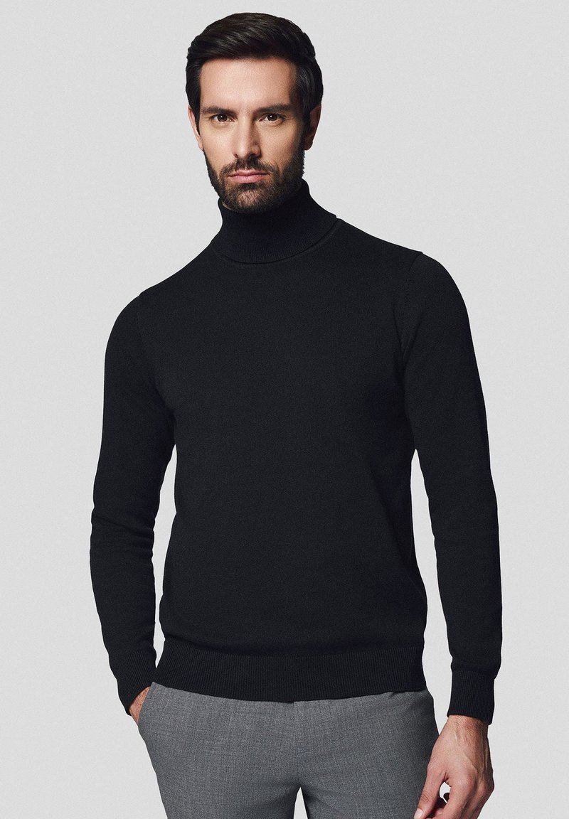 Czarny sweter z golfem, dopasowany krój, prążkowany dekolt i dół, wykonany z teksturowanej dzianiny. W połączeniu z szarymi spodniami.