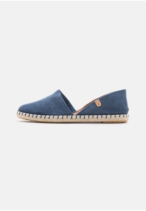 Chaussure plate espadrille en daim bleu avec semelle naturelle en corde tressée et petite étiquette de marque marron clair sur le dessus.