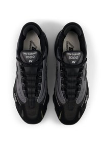 Μαύρα αθλητικά παπούτσια κατασκευασμένα από δίχτυ και συνθετικό υλικό, με στρογγυλεμένη μύτη, επενδεδυμένο κολάρο και διακριτικές γκρι λεπτομέρειες. Ορατά κορδόνια και λογότυπο.