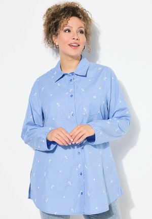 Camicia button-up azzurro chiaro realizzata in tessuto con ricami floreali bianchi. Presenta colletto, maniche lunghe e taschino sul petto.