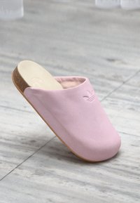 Chinelo rosa com um upper suave e texturizado e sola de cortiça moldada. Apresenta um logotipo em relevo discreto na parte frontal. Design redondeado e aberto na parte de trás.