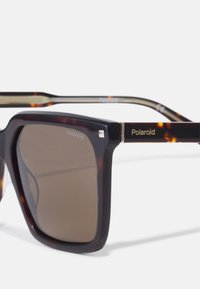 Ochelari de soare tortoise-shell maronii cu rame patratoase, având lentile polarizate. Accente aurii cu numele mărcii "Polaroid" pe braț.