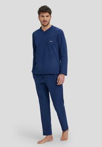 Conjunto de lounge en azul marino hecho de tela suave; camiseta de manga larga con un bolsillo y escote en V, acompañada de pantalones ajustados a juego.