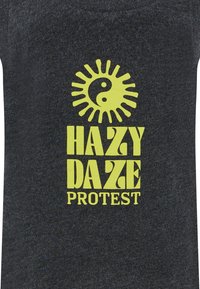 T-shirt di tessuto grigio scuro con una grafica di un sole giallo e del simbolo yin-yang, accompagnato dalla scritta: "HAZY DAZE PROTEST" in un font audace e stilizzato.