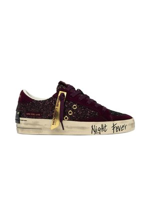 Sneaker low-top viola scuro con glitter, occhielli dorati, un'etichetta gialla e testo "Night Fever" sulla suola bianca consumata.