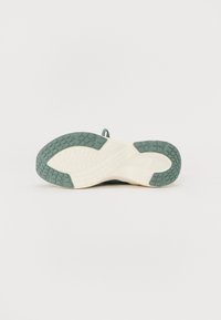 La suola delle scarpe presenta un'outsole in gomma verde con texture e un midsole avorio chiaro con motivi di trazione per grip e stabilità.