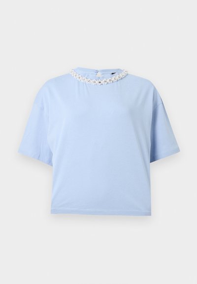 Ανοιχτό μπλε κοντομάνικο τοπ με στρογγυλή λαιμόκοψη, διακοσμημένο με λευκή κεντητική λουλουδιών και μικρές πέρλες, σε μονόχρωμο φόντο.
